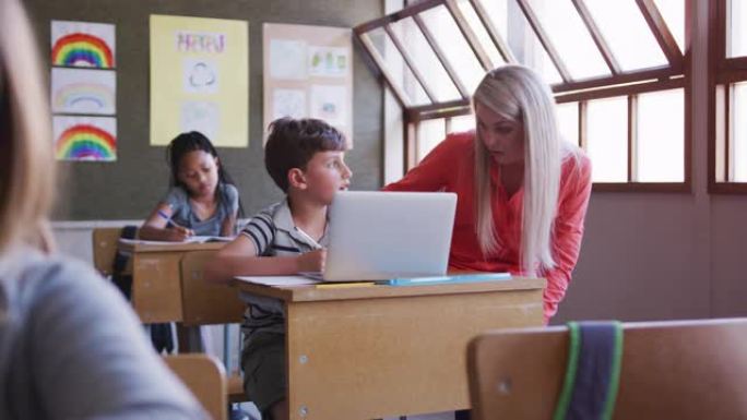 女教师和男孩在学校课堂上使用笔记本电脑