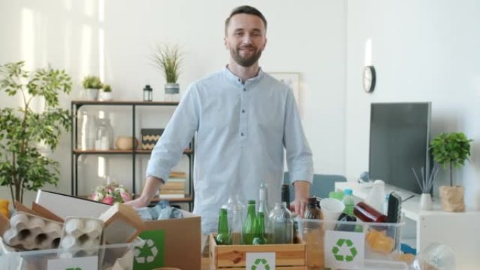 微笑的家伙站在公寓里的肖像，里面装满了垃圾的回收容器