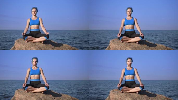 一位健康美丽的瑜伽老师，有着绿松石般的头发，正在冥想，坐在鹅卵石上，靠着大海和天空