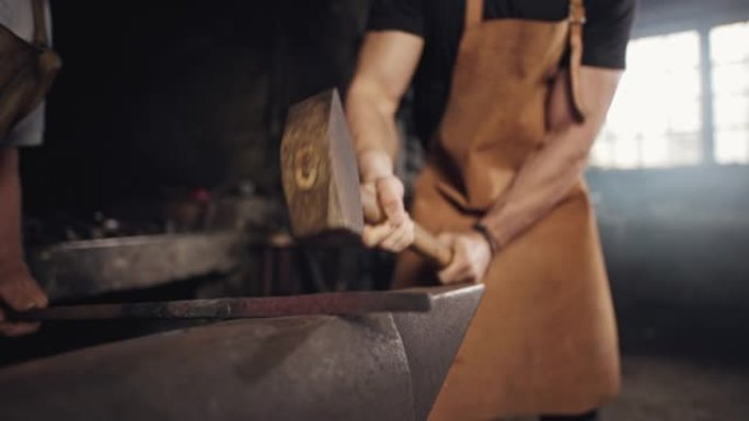 SLO MO两个铁匠用铁锤在铁砧上敲打金属片