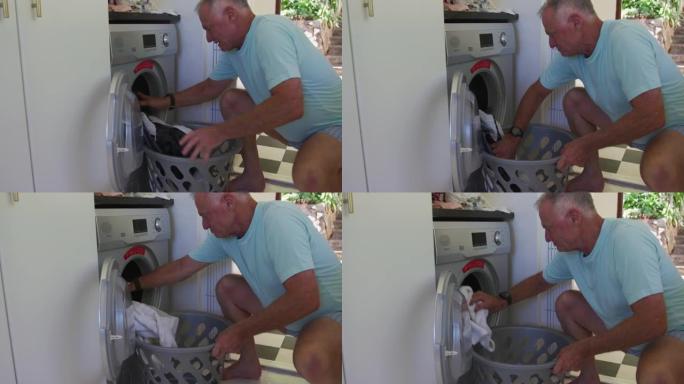 高加索高级男子在家将衣服放在洗衣机中