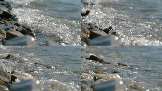 特写: 膨胀冲刷在空旷的海岸线上散落的圆形石头上。