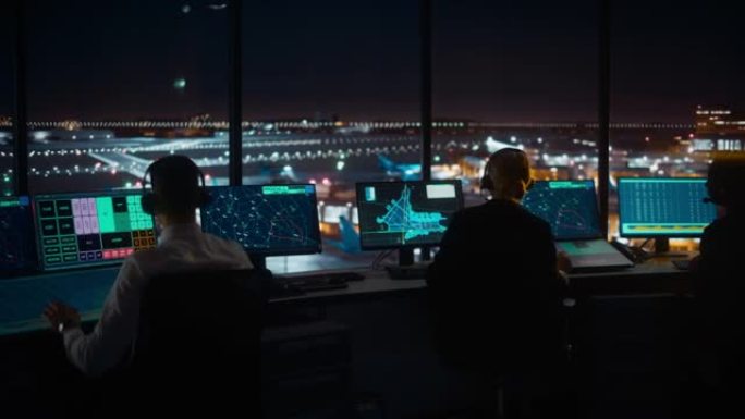 夜间在现代机场塔台工作的多元化空中交通管制团队。办公室里满是台式电脑显示屏，配有导航屏幕、飞机起飞和