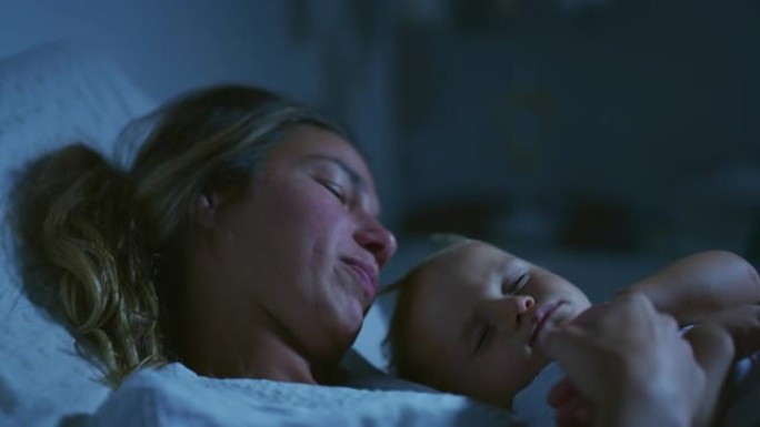 年轻的和平的neo母亲的真实电影拍摄是在晚上在托儿所的床上睡觉时爱抚她的新生婴儿。