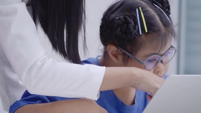 特写，老师与亚洲唐氏综合症女孩10岁女学生在小学教室里教电脑。残疾收集2019