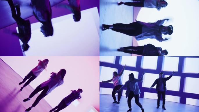 在工作室环境中的虚拟制作过程中，由三个舞者组成的不同组的旋转镜头在带有VFX动画的大Led墙屏幕前表