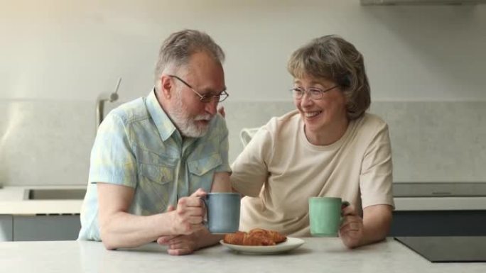 老年夫妇坐在厨房吃早餐，享受谈话
