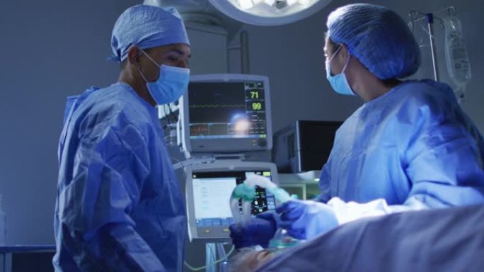 混血外科医生穿着防护服在手术室看心脏监护仪