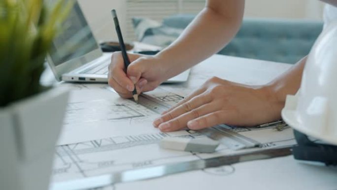 建筑师在家工作时，女性双手在蓝图上绘制的特写镜头