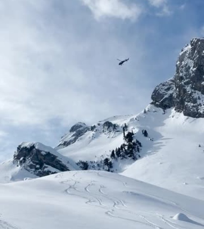 低角度视图: 直升机飞越白雪皑皑的山峰，滑雪者开始骑行