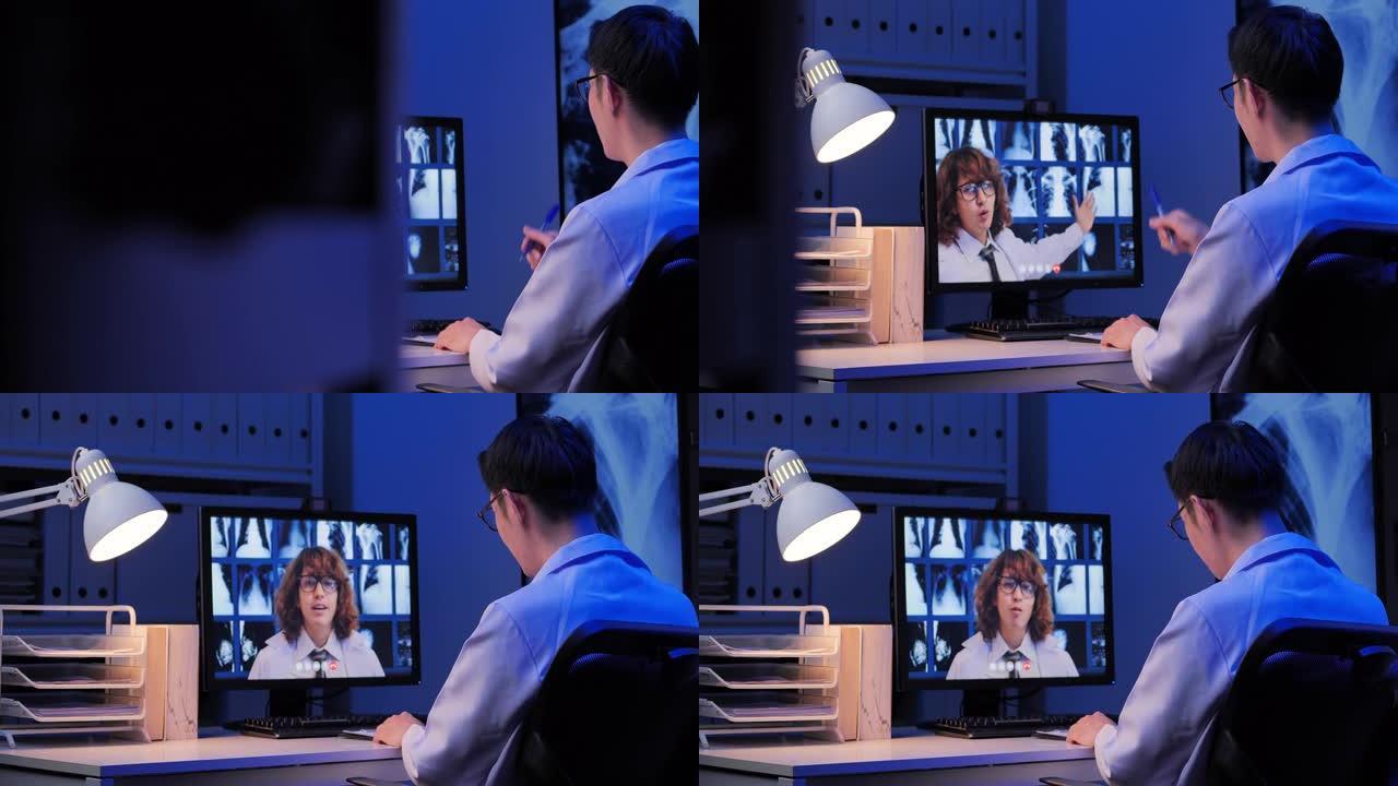 亚洲男性医生视频电话给白人男性教育医生关于视频会议上骨骼的研究x射线，而在深夜工作的家中通过计算机进