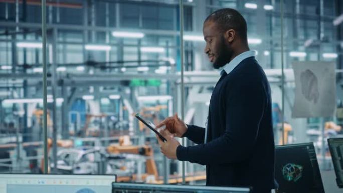 汽车厂办公室: 成功的黑人男性总工程师肖像在自动化机器人手臂装配线上使用平板电脑制造高科技电动汽车。