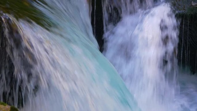 特写: 野山河流过苔藓岩石，形成小瀑布