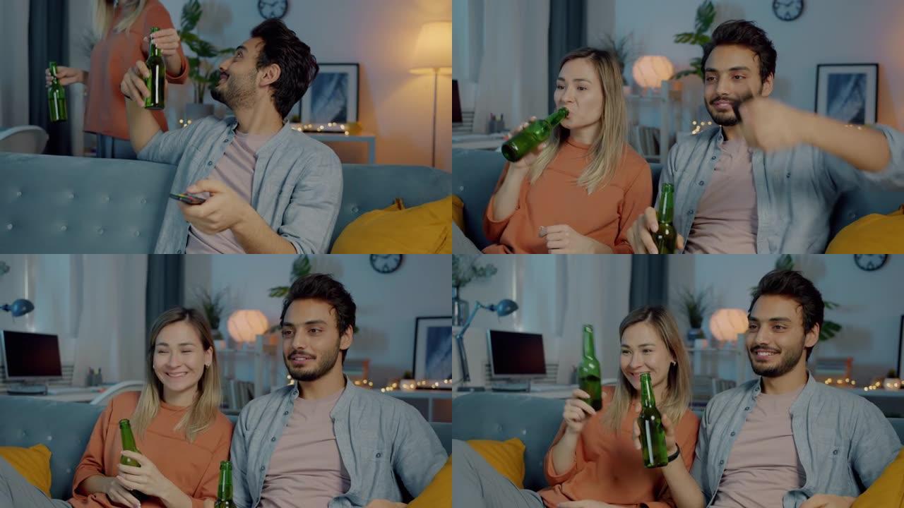 无忧无虑的女人带一瓶啤酒给男朋友看电视，晚上在家喝酒