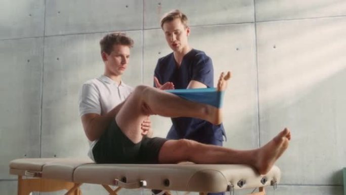 运动理疗专家向年轻的男运动员展示如何在特定的肌肉群或关节上拉伸橡皮筋。运动员从轻度受伤中恢复过来，正
