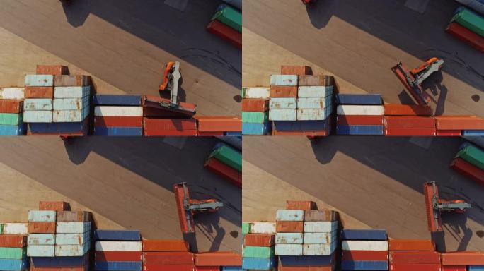 在船厂码头运送大型红色货物集装箱的集装箱搬运工的空中无人机镜头。机器的驾驶员正在物流中心仓库中装载板