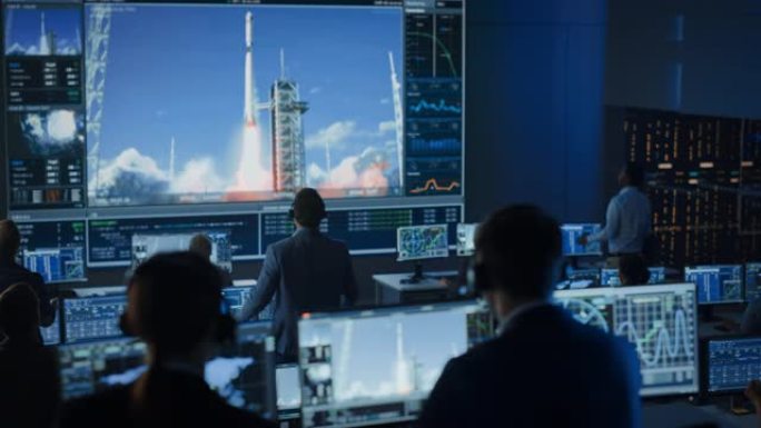 任务控制中心的一群人见证了太空火箭的成功发射。飞行控制员工坐在前面的计算机显示屏上，监视人员的任务。