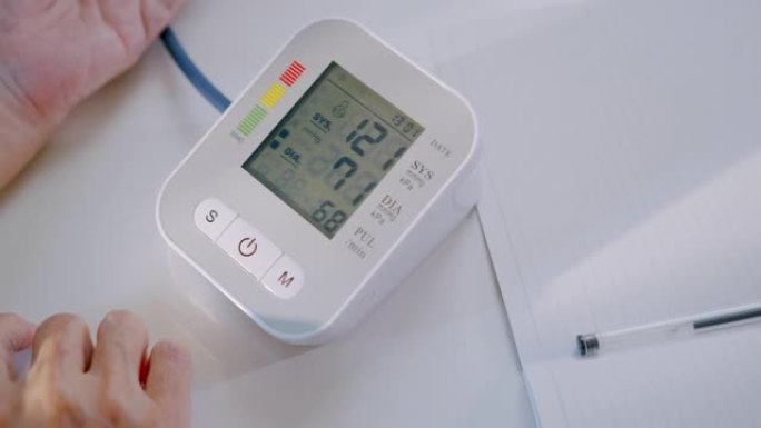 高级妇女使用医疗器械在家中检查血压计和心率。