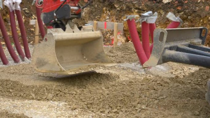特写: 挖掘机铲斗在施工现场平湿砾石。