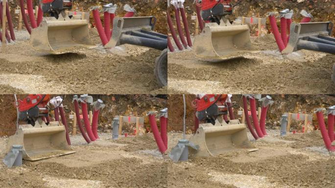 特写: 挖掘机铲斗在施工现场平湿砾石。