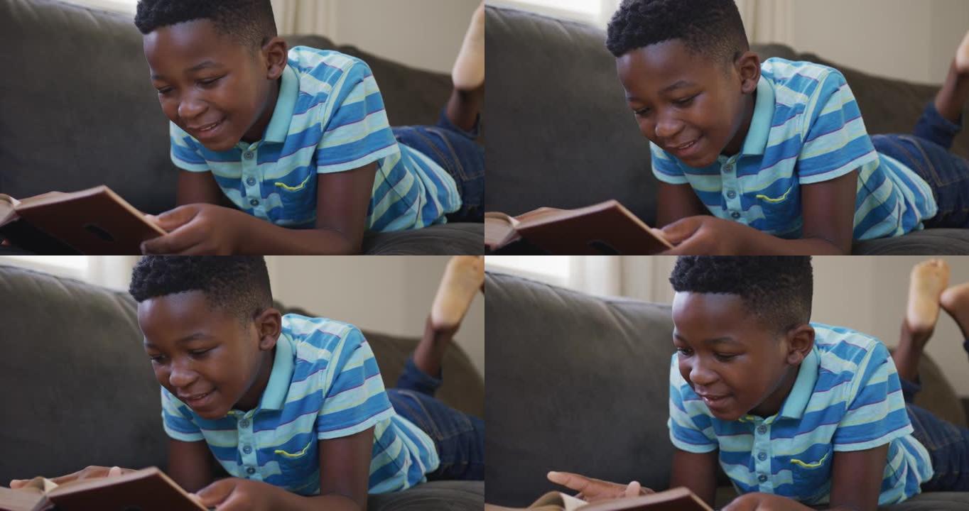 非裔美国男孩躺在家里的沙发上看书