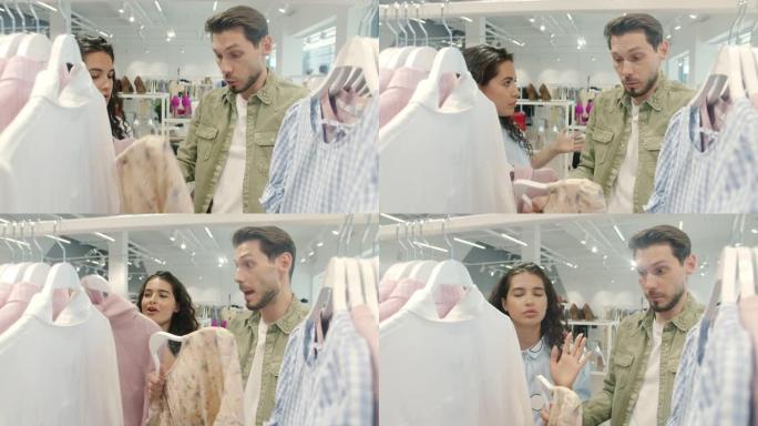 不快乐的夫妇在商店里打架，选择衣服大喊大叫和打手势拿着衣服