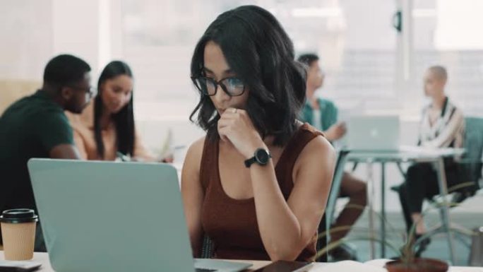 4k视频片段，一个年轻的女商人坐在办公室里，用笔记本电脑看起来很沉思