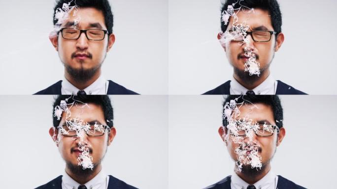 4k视频片段，一个年轻人在工作室背景下用五彩纸屑喷在脸上