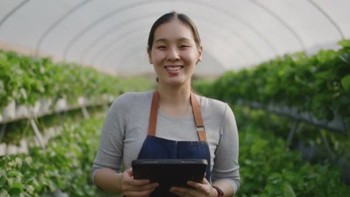 自信的亚洲妇女与数字平板电脑在温室