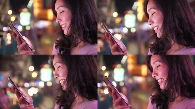 亚洲妇女晚上在街上使用手机