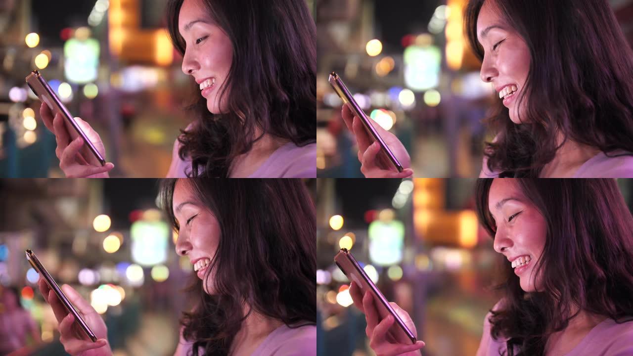 亚洲妇女晚上在街上使用手机
