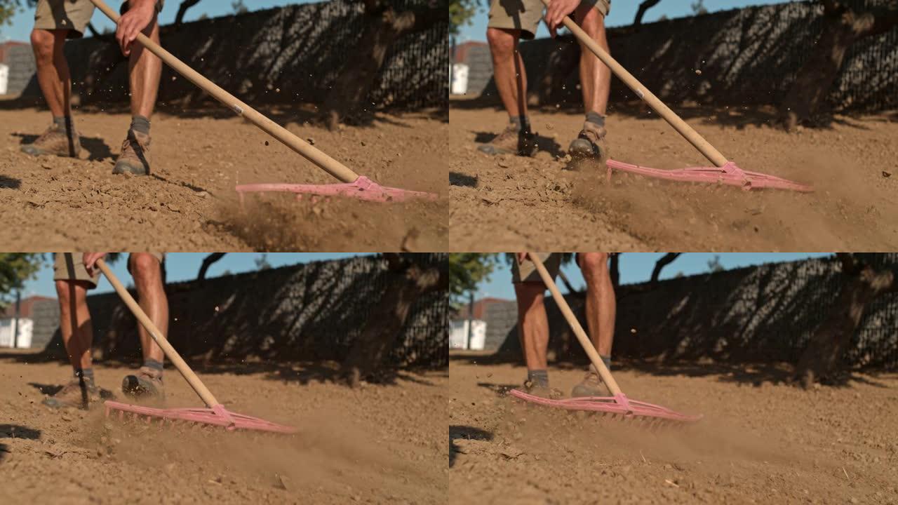 超级SLO MO园丁使用耙子将房屋后面草坪上的土壤夷平