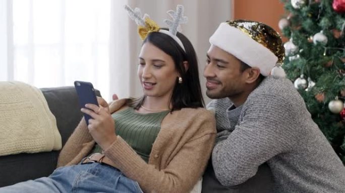 一对年轻夫妇在家中一起在沙发上使用手机进行圣诞节最后一刻购物的4k视频片段