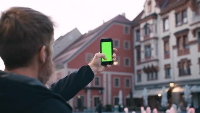 留着长胡须的男人在城市用智能手机拍照