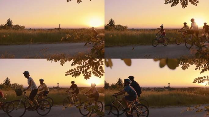 SLO MO家庭带着三个孩子在日落时在乡间小路上骑自行车