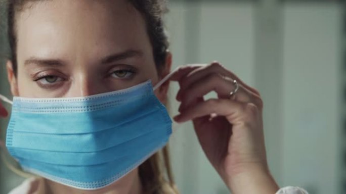医院女护士或女医生上班前戴医用防护口罩微笑的电影微距镜头。新冠肺炎概念、防护、冠状病毒、安全、保健