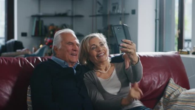 一对可爱的高级夫妇正在客厅用智能手机自拍。