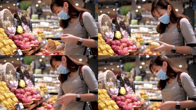 戴着医用口罩的年轻亚洲妇女在超市里用杂货店推车走路