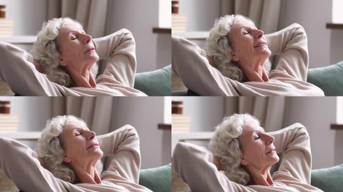 退休的成熟白衣女人在舒适的沙发上做白日梦。