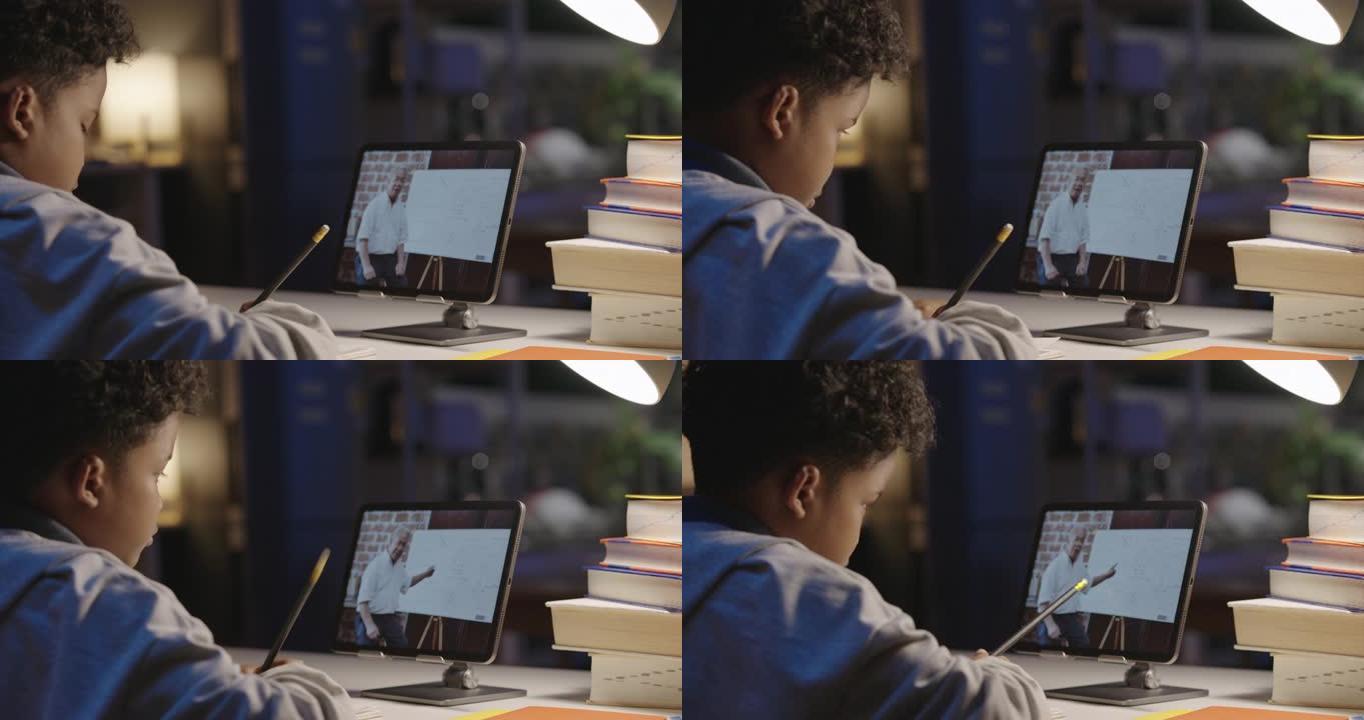 后视图，9岁男孩的非裔美国人在平板电脑上通过视频通话与导师老师在家上学时，晚上呆在家里。家庭教育和远