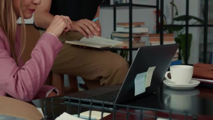 合作理念。两个快乐美丽忙碌的年轻商务女性在现代办公桌上用笔记本电脑微笑。