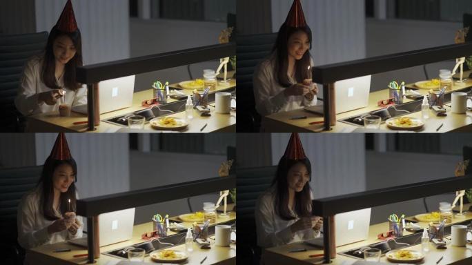 亚洲华裔美女独自在办公室工作到很晚，与她在其他分支机构的同事庆祝生日视频会议