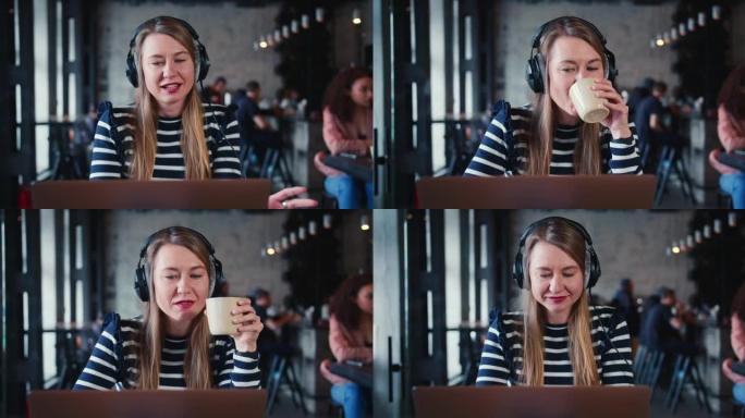 年轻快乐微笑的女性金发信息技术自由工作者使用笔记本电脑，耳机在时尚咖啡馆在线与朋友聊天