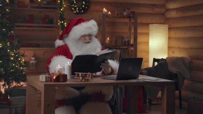 圣诞老人在视频聊天中结束了对话，拿了一本书，开始愉快地阅读
