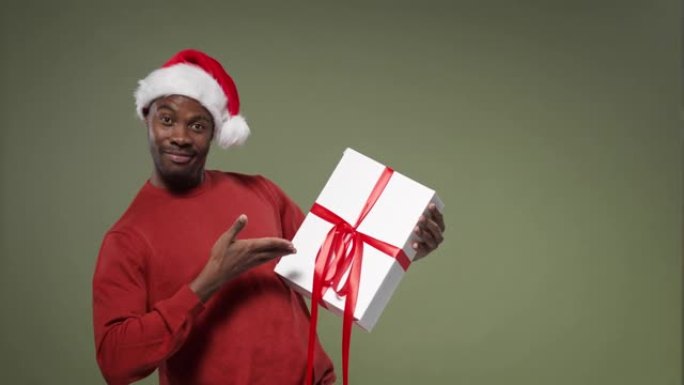 一个戴着圣诞帽和红色针织毛衣的黑皮肤男人转身从四面八方检查礼品盒