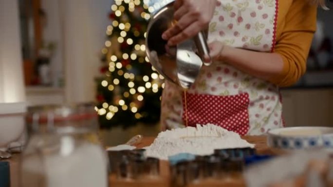 女人在烘烤圣诞节饼干时将搅打的鸡蛋倒入面粉中
