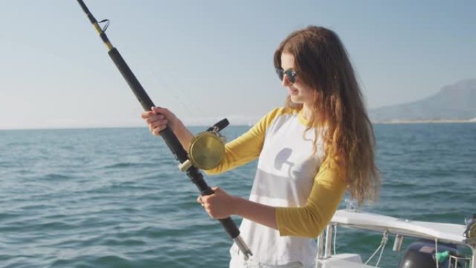 一个十几岁的高加索女孩在船上钓鱼的侧视图