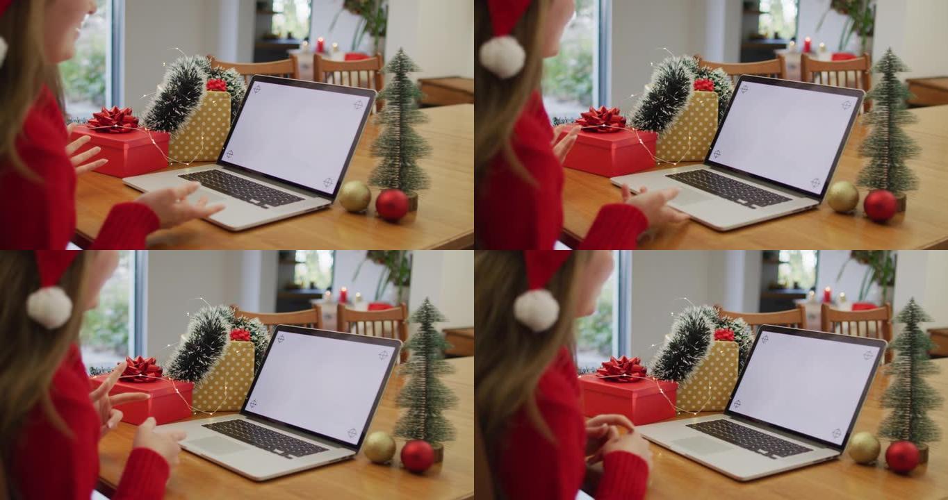 戴着圣诞老人帽子的白人妇女在笔记本电脑上在家进行视频通话，屏幕上有复制空间