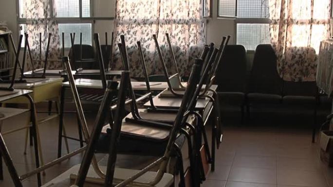 在冠状病毒大流行期间，阿根廷封闭的公立学校的老式胶合板和金属学校椅子颠倒在空旷的教室里。
