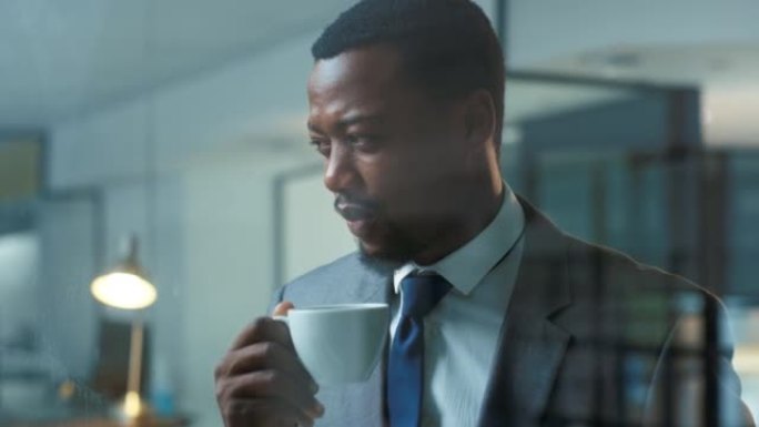 自信的商人站在现代办公室时看起来很体贴，喜欢喝杯咖啡。一名职业男性企业家和商业领袖喝茶享受休息